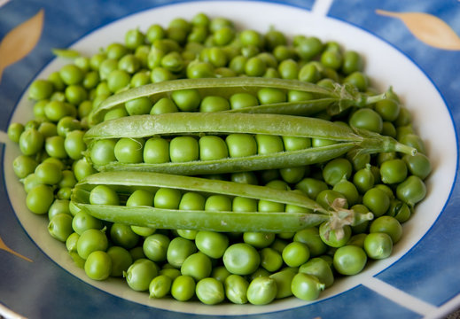 Green pea pods on bed of peas