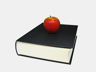 Fresh red apple above black large book on white background