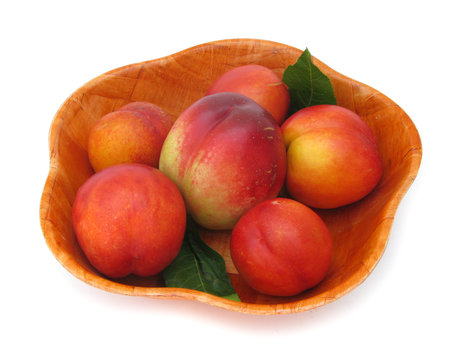 Nectarines with leaves in wooden dish