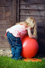 Little girl playing with large red ball