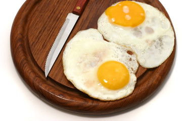 served fried egg on wooden plate with knife
