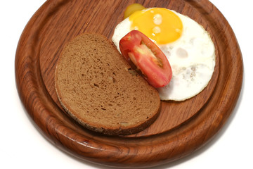 served fried egg on wooden plate with tomato and bread