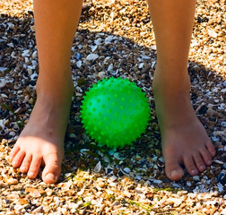 Child Feet on sand at green ball