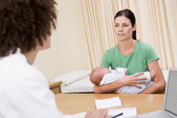 Doctor with laptop and woman in doctor's office holding baby