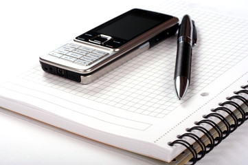 Pen, spiral notepad and mobile phone on white background
