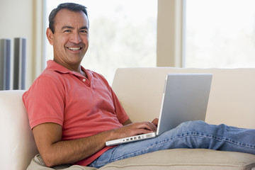 Man in living room using laptop smiling
