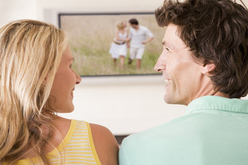Couple in living room watching television smiling