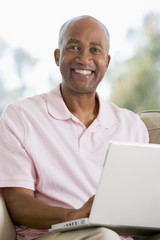 Man in living room using laptop and smiling