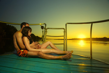 Couple in sunset hug on boat