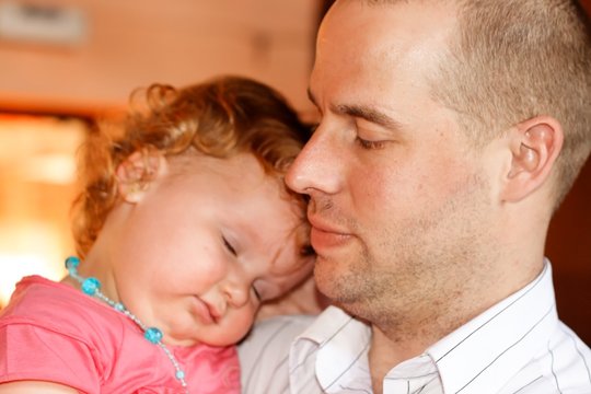 Un b&eacute;b&eacute; dormant dans les bras de son papa