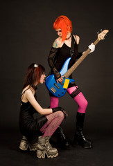 Two rock girls, one of them licking guitar