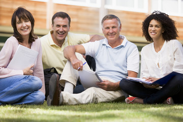 Adult students sitting on a campus lawn