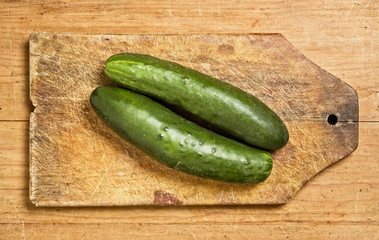 Two cucumbers on a wooden kitchen table.