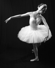The girl in a ballet suit on a black background