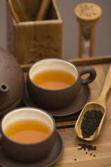 Tea serving in brown cups with teapot and wooden cutlery