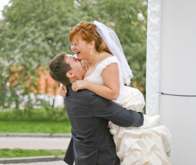 Fototapeta premium groom embracing laughing plump bride in the park