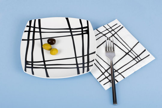 three olivs in the white plate and fork