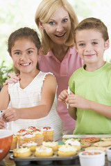 Woman with two children decorating cookies smiling
