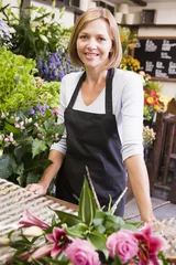 Foto auf Acrylglas Blumenladen Frau, die im Blumenladen arbeitet, lächelt