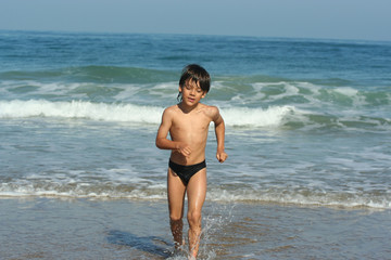 Fototapeta premium petit garçon entrain de courir sur la plage