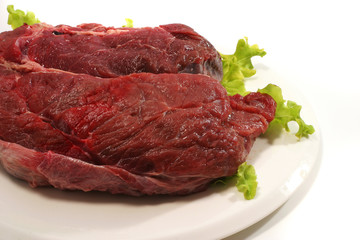 raw beef meat and salad over white on dish
