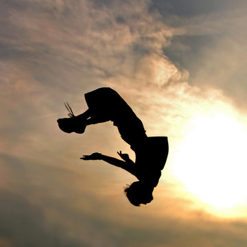 silhouette of jumping man against sky and clouds