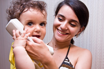 Mum holds on hands the child who speaks in a telephone tube