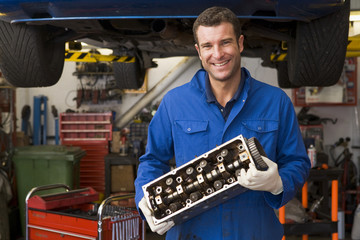 Mechanic holding car part smiling