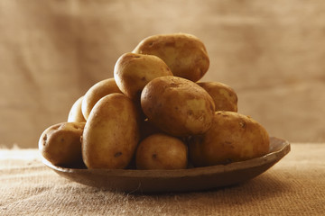 raw potatoes on plate with burlap rustic background