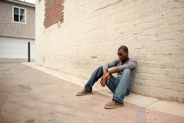 Depressed Young African American Man Leaning Against Alley Wall