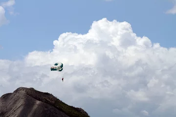 Fotobehang Luchtsport Vliegende parachute op achtergrond met lucht en bergen