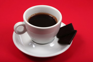 white coffee cup on red background with chocolate