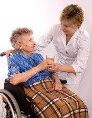 Health care worker and elderly woman in wheelchair needs help