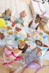 Young children at party sitting at table with food smiling