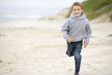 Young boy running on beach smiling