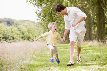 Father and son running on path holding hands smiling