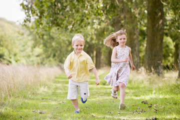Fototapeta premium Two young children running on path smiling