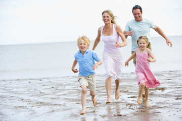 Family running on beach smiling