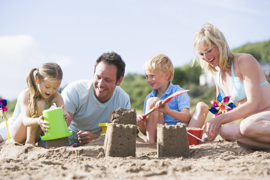 Family On Beach Making Sand Castles Smiling