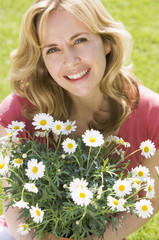 Woman outdoors holding flowers smiling