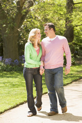 Couple walking on path holding hands smiling