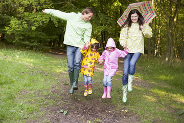 Fototapeta premium Family outdoors skipping with umbrella smiling