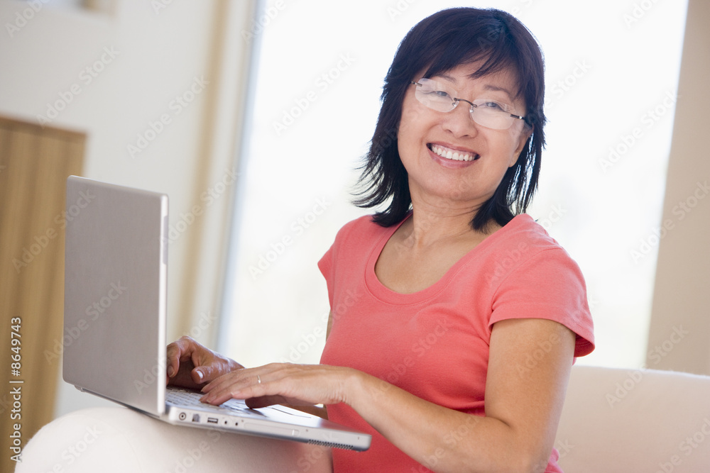 Wall mural woman in living room with laptop smiling