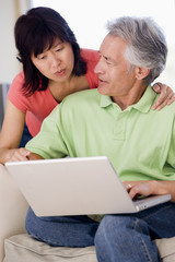 Couple in living room with laptop smiling