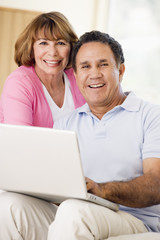 Couple in living room with laptop smiling