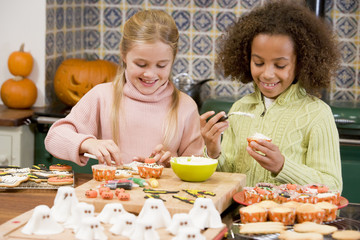 Two young girl friends at Halloween making treats and smiling