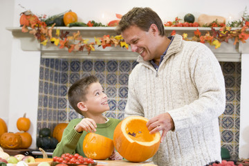 Father and son carving jack o lanterns on Halloween and smiling