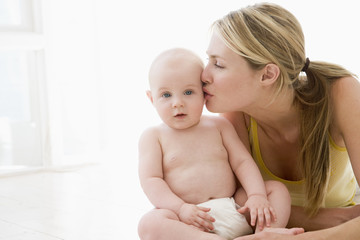 Mother kissing baby indoors