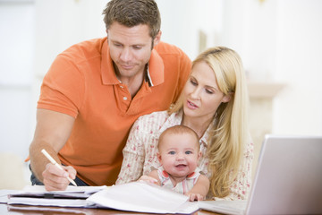 Couple and baby in dining room with laptop