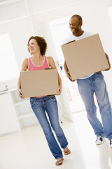 Fototapeta na wymiar Couple with boxes moving into new home smiling